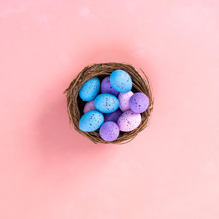 Happy easter. Colorful easter eggs in nest on pastel color background with space for text.