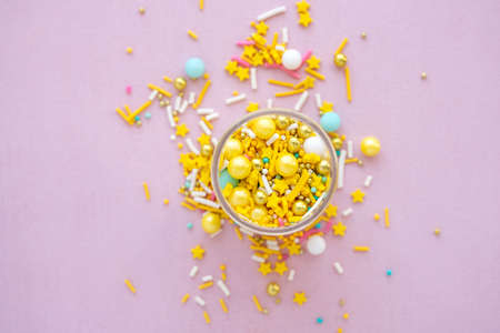 Yellow sugar sprinkles grainy on pink background, close-up flat layの写真素材