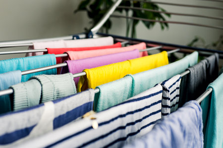 Laundry day Rainbow color clothes hanging on washing line to dry indoors homeの写真素材