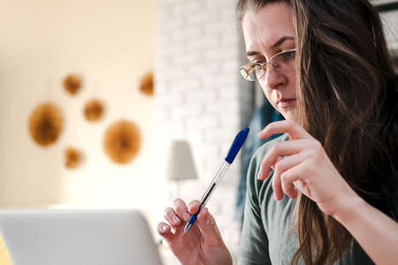 Work from home. Middle aged brunette woman with glasses works at home online.の写真素材