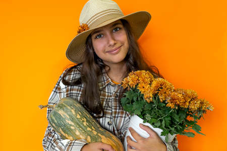 Girl in hat holds autumn harvest pumpkinの写真素材