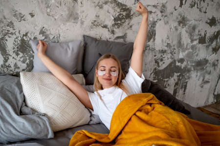 Girl pulls herself up while lying in bedの写真素材