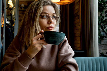 Middle-aged blonde caucasian woman drinks coffee in cafeの写真素材