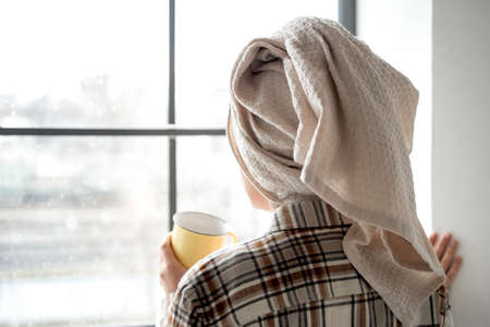 Young woman with towel on her head drinking coffeeの写真素材