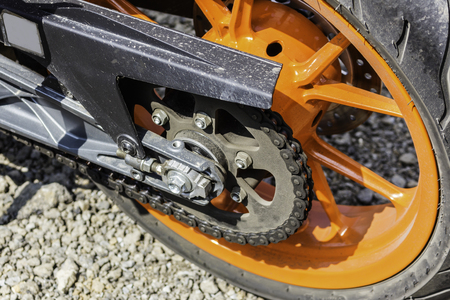 Rear orange wheel and chain of sport bike. Close up shot