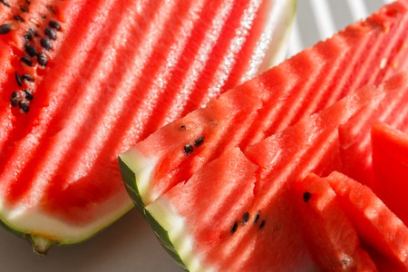 slices pieces red watermelon, sunlight stripes on blue plateの写真素材