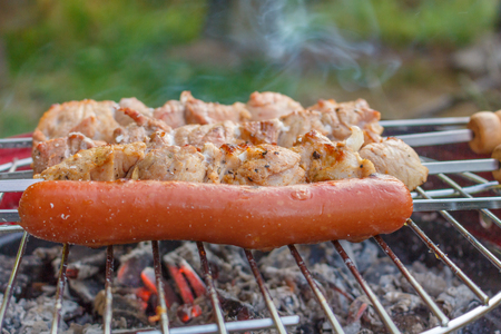 Close up barbecue grill with meat and sausages cooking during summer garden partyの写真素材
