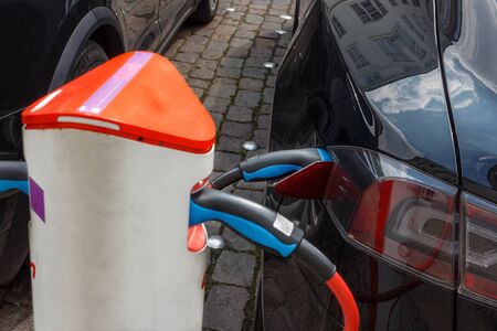 The power supply plugged into an electric car during charging in Copenhagen. Close up Electric car charging station.の写真素材