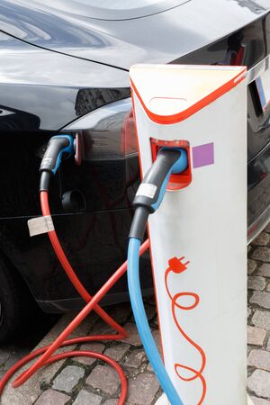 The power supply plugged into an electric car during charging in Copenhagen. Close up Electric car charging station.の写真素材