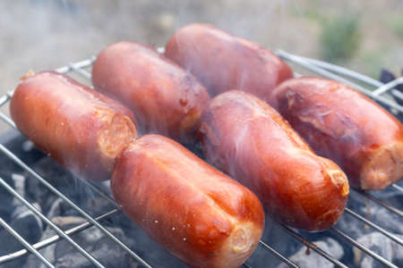 Close up barbecue grill with meat and sausages cooking during summer garden partyの写真素材