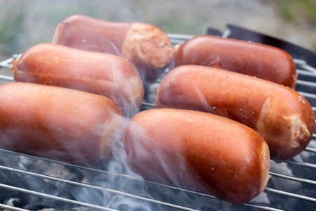 Close up barbecue grill with meat and sausages cooking during summer garden partyの写真素材