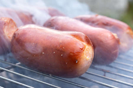 Close up barbecue grill with meat and sausages cooking during summer garden partyの写真素材