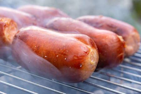 Close up barbecue grill with meat and sausages cooking during summer garden partyの写真素材