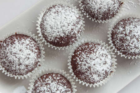 Several chocolate muffins on the white square plate. Shallow focus. Top view.の写真素材