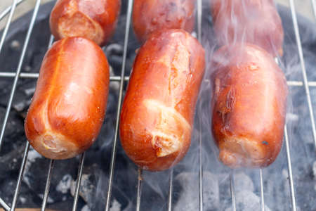 Close up barbecue grill with meat and sausages cooking during summer garden partyの写真素材