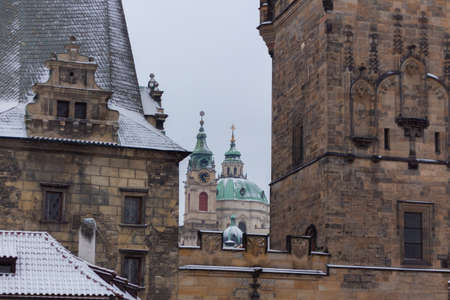 Prague, Charles Bridge with St. Nicolas Church behind Bridge Tower snow winterの写真素材