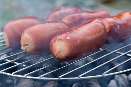 Close up barbecue grill with meat and sausages cooking during summer garden partyの写真素材