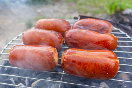 Close up barbecue grill with meat and sausages cooking during summer garden partyの写真素材
