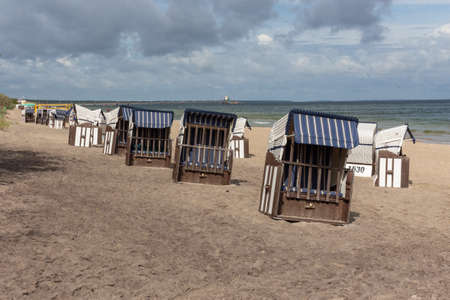 Lonely beach wooden wicker chairs on beach cloud sky Baltic Sea, Germanyの写真素材