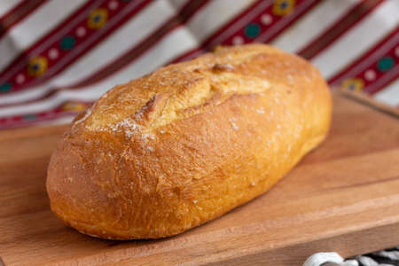 fresh white bread on brown wood cutting board on tableclothの写真素材
