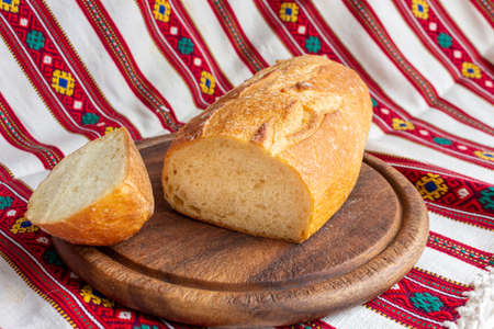 fresh white bread on brown wood cutting board with sliced pieces of breadの写真素材