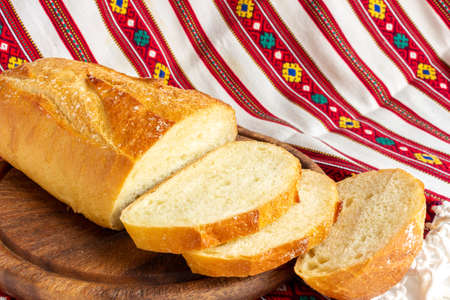fresh white bread on brown wood cutting board with sliced pieces of breadの写真素材