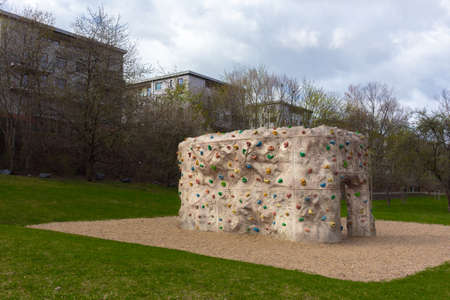 A climbing bouldering rock wall with grip for hands and feet outdoor in parkの写真素材