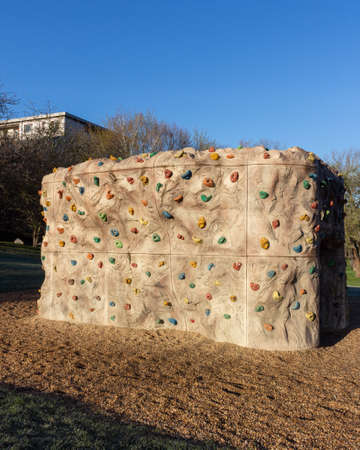 A climbing bouldering rock wall with grip for hands and feet and rope outdoor in park