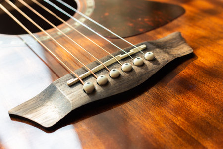 Acoustic guitar bridge with one pins and strings close up with selective shallow focus.の写真素材