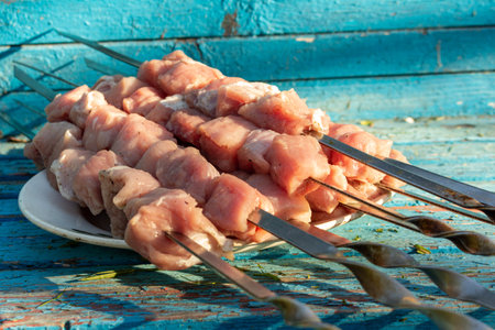 Raw meat skewers on a plate on rustic blue wooden background before grillingの写真素材