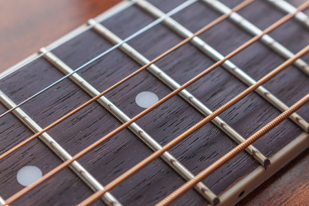 Guitar neck, stretched strings, frets and texture of natural material neck with selective shallow focus.の写真素材