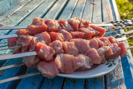 Raw meat skewers on a plate on rustic blue wooden background before grillingの写真素材