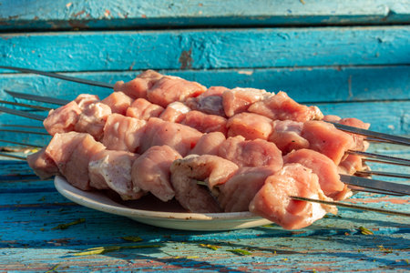 Raw meat skewers on a plate on rustic blue wooden background before grillingの写真素材