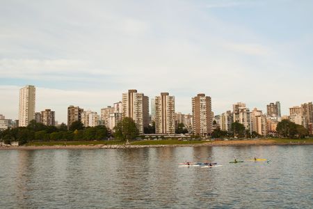 Vancouver skyline viewed from the water with blue sky and white clouds and kayakers in the foregroundの写真素材