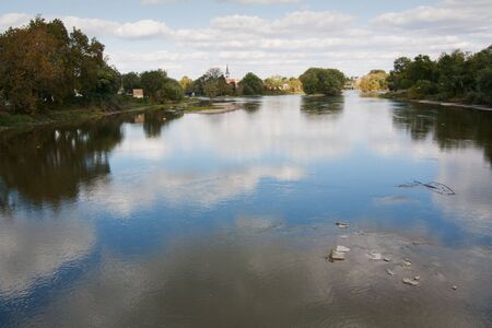 View of the Wabash River from a bridge near Logansport, Indiana, with bright  blue sky and white clouds reflected in the waterの写真素材