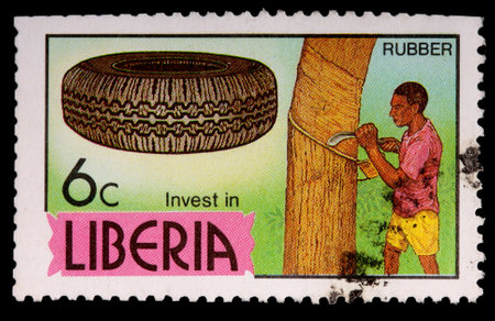 LIBERIA - CIRCA 1981: A 6-cent stamp printed in Liberia shows a tire and a man tapping a rubber tree for latex to encourage investment, circa 1981のeditorial素材