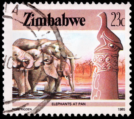ZIMBABWE - CIRCA 1985: A 23-cent stamp printed in the Republic of Zimbabwe shows several elephants drinking water at pan, circa 1985のeditorial素材