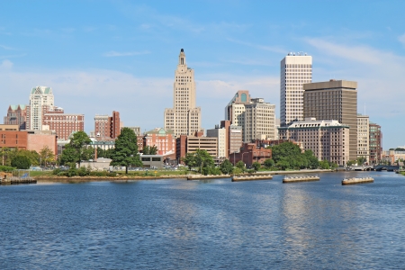 View of the skyline of Providence, Rhode Island, from the far side of the Providence River against a blue sky and white cloudsの写真素材