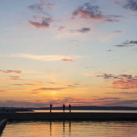 People silhouettes on lake quay in eveningの写真素材