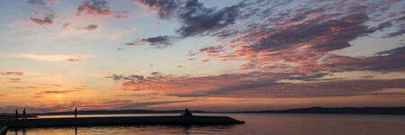Panorama of sunset on lake and people silhouettesの写真素材