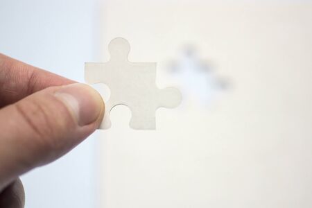 Hand holds suitable piece of puzzleの写真素材