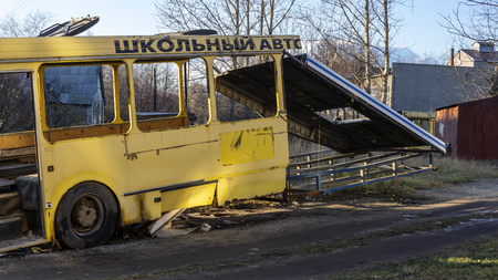 Wreckage bus carcass of yellow school bus in urban wastelandの写真素材