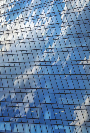 Sky and white clouds are reflected in glass skyscraper