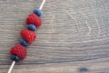 Juicy garden raspberry and blueberries on a skewerの写真素材