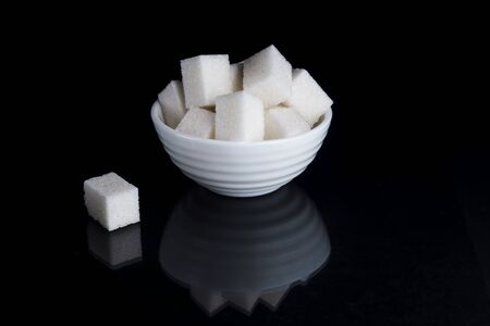 Sugar cubes in sugar bowl on black backgroundの写真素材