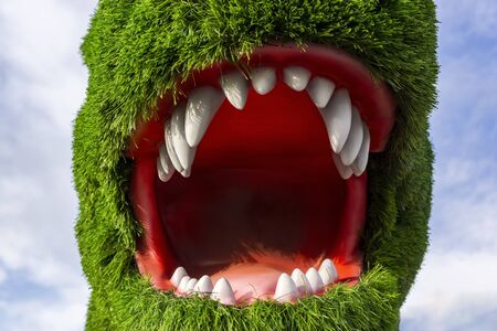Dinosaur head with open mouth covered with artificial green grassの写真素材