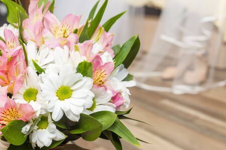 Bride bouquet of flowers, wedding white veil and festive shoes on bedの写真素材