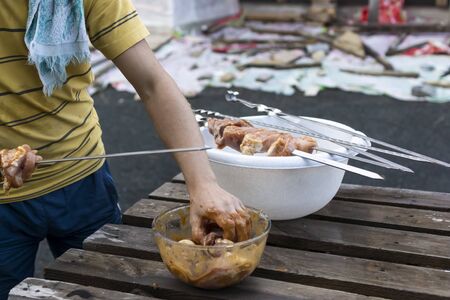 Hands push juicy pickled meat on skewers to grill on barbecue for picnicの写真素材