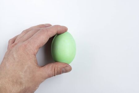 Hand holds green easter egg against white background, concept