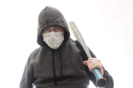 Criminal in a hoodie and mask with a black baseball bat on his shoulderの写真素材